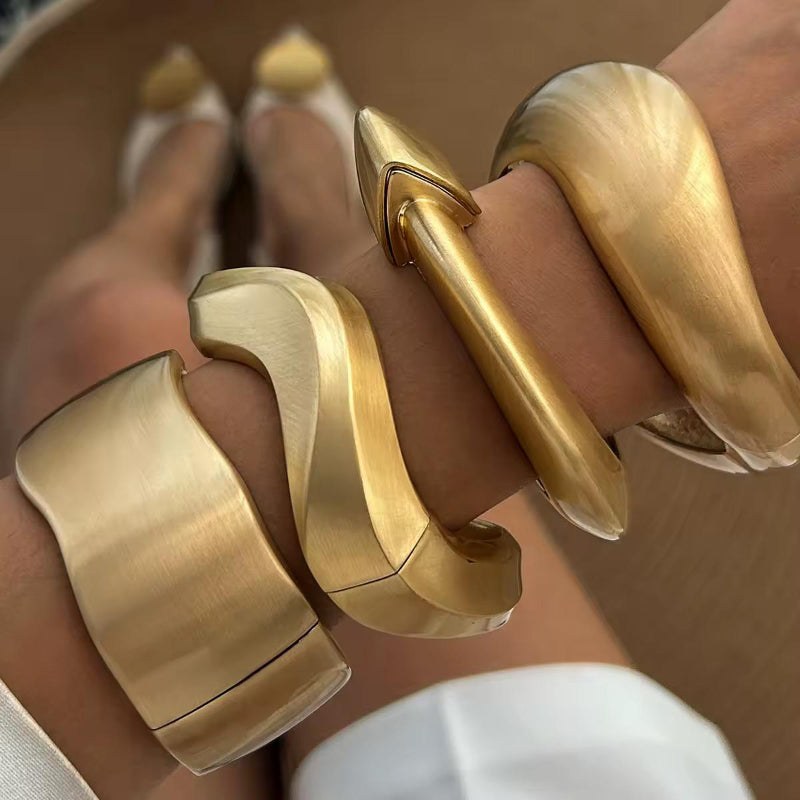 Striking wide gold cuff bracelet with artistic shape, unisex design inspired by modern sculpture