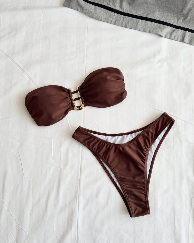 Elegant Brazilian-style bikini set in deep chocolate brown with bandeau top and low-rise bottom, made of seamless nylon-spandex fabric with gold ring detail – displayed on white background.