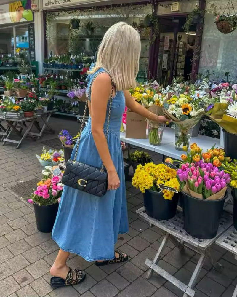 Woman wearing sleeveless backless denim dress with O-neckline – summer 2025 fashion trend