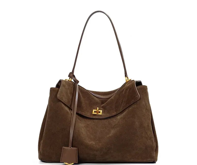 Elegance Suede Handbag is a true masterpiece crafted from high-quality suede, blending luxury and functionality perfectly. Available in two elegant colors – Light Brown and Dark Brown – this exquisite bag features a sophisticated gold buckle, enhancing its design and adding a modern yet timeless look. With generous dimensions of 23 cm x 11 cm x 35 cm, it offers ample space for all your essentials, from smartphones to cosmetics and more, making it the ideal companion for any occasion.
