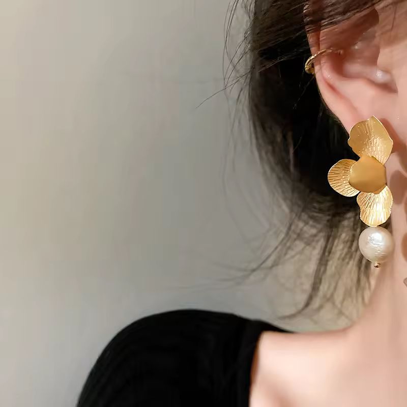 Pair of luxurious gold-toned blossom earrings with lustrous white freshwater pearls on white background