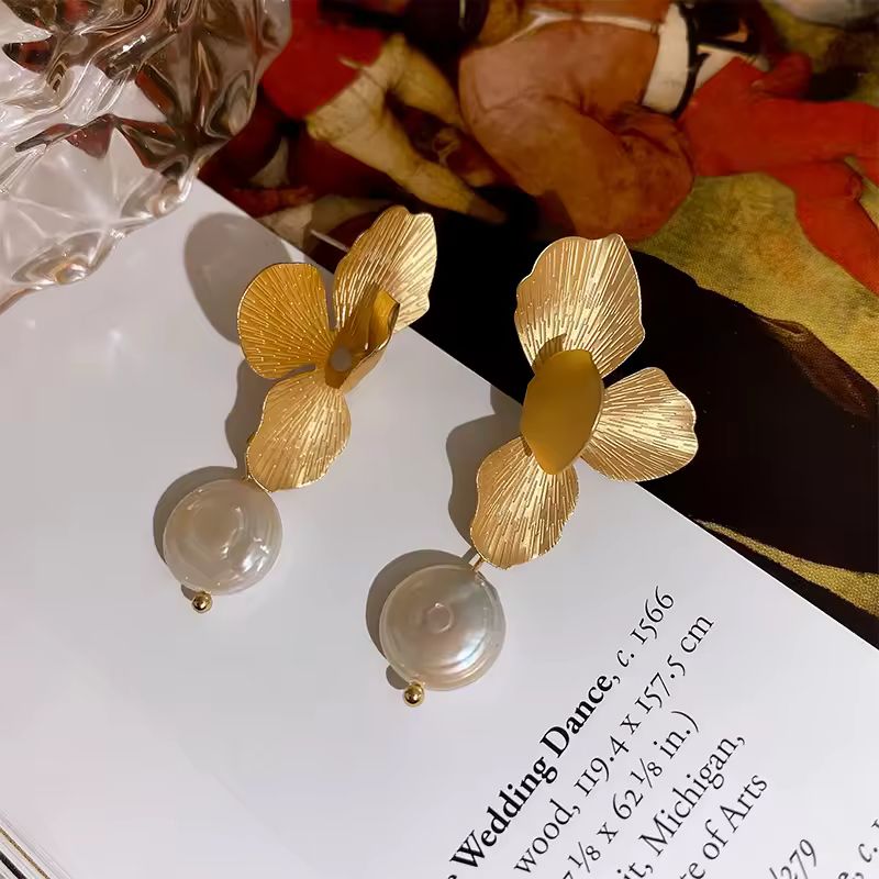Pair of luxurious gold-toned blossom earrings with lustrous white freshwater pearls on white background
