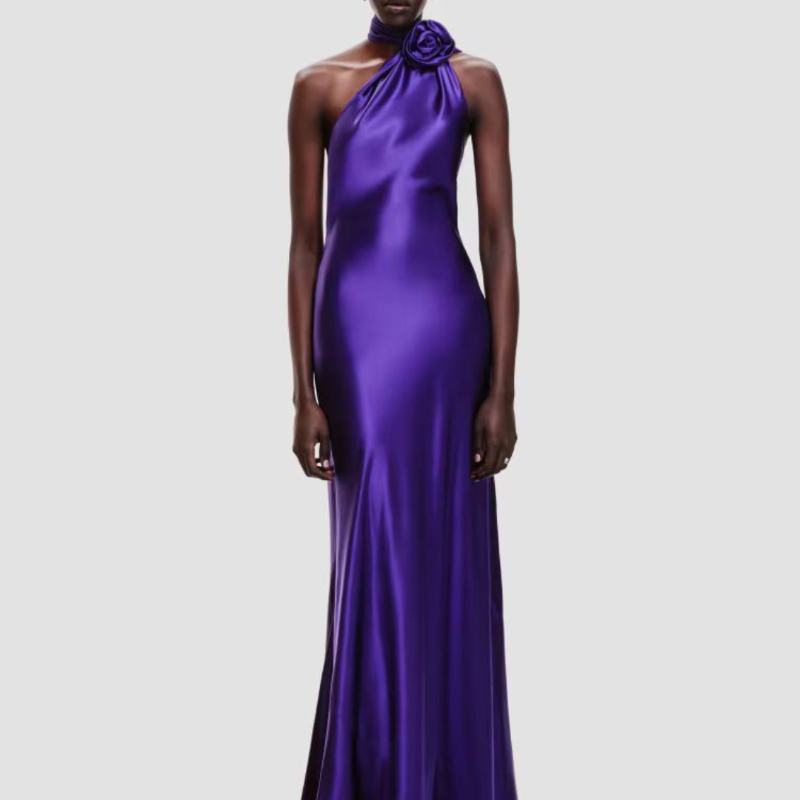 Model wearing long purple satin evening dress with 3D flower detail and backless design – Glamour Mia