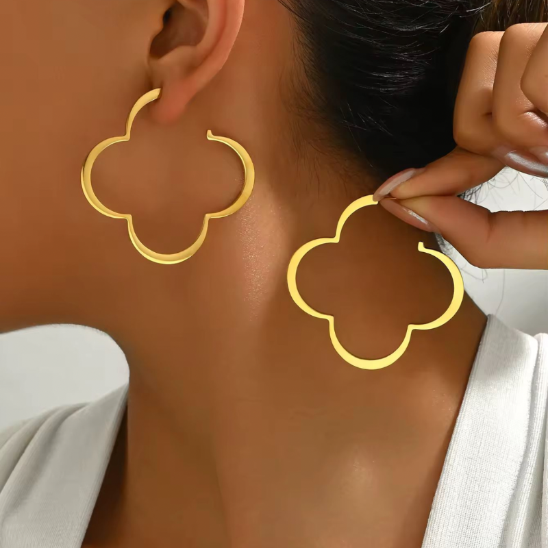 Trendy gold floral statement hoop earrings worn on ear – large clover-shaped copper earrings for women, fashion jewelry 2025