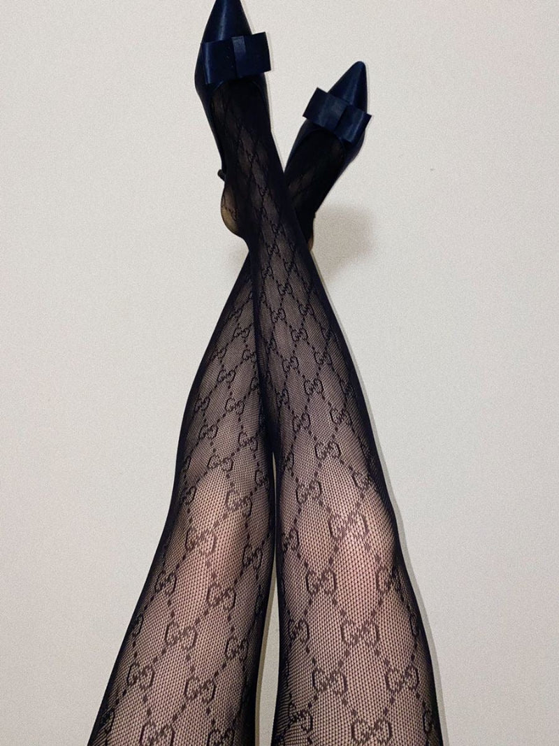 Black patterned tights styled with a dress — chic luxury-inspired fashion look for women.
