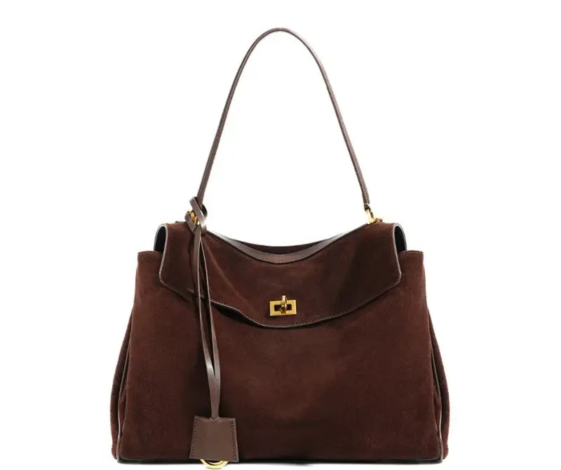The Elegance Suede Handbag is a true masterpiece crafted from high-quality suede, blending luxury and functionality perfectly. Available in two elegant colors – Light Brown and Dark Brown – this exquisite bag features a sophisticated gold buckle, enhancing its design and adding a modern yet timeless look. With generous dimensions of 23 cm x 11 cm x 35 cm, it offers ample space for all your essentials, from smartphones to cosmetics and more, making it the ideal companion for any occasion.