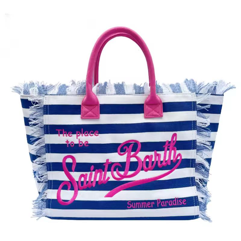 Close-up of thick canvas beach bag with The place to be – Saint Barth” print and raw fringe edges in bohemian summer style.