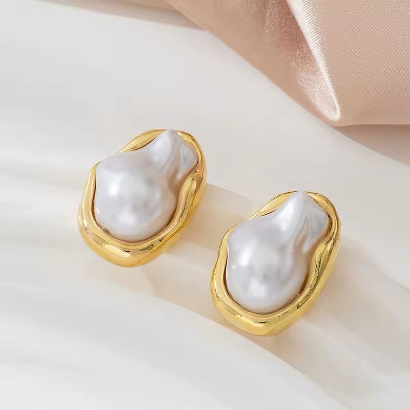 ZAYA gold pearl earrings – sculpted baroque-style faux pearl studs on soft satin background.