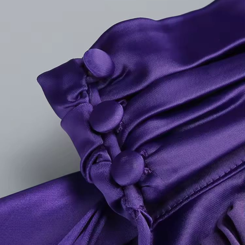 Side profile of woman in glamorous purple evening dress with draped fabric and open back