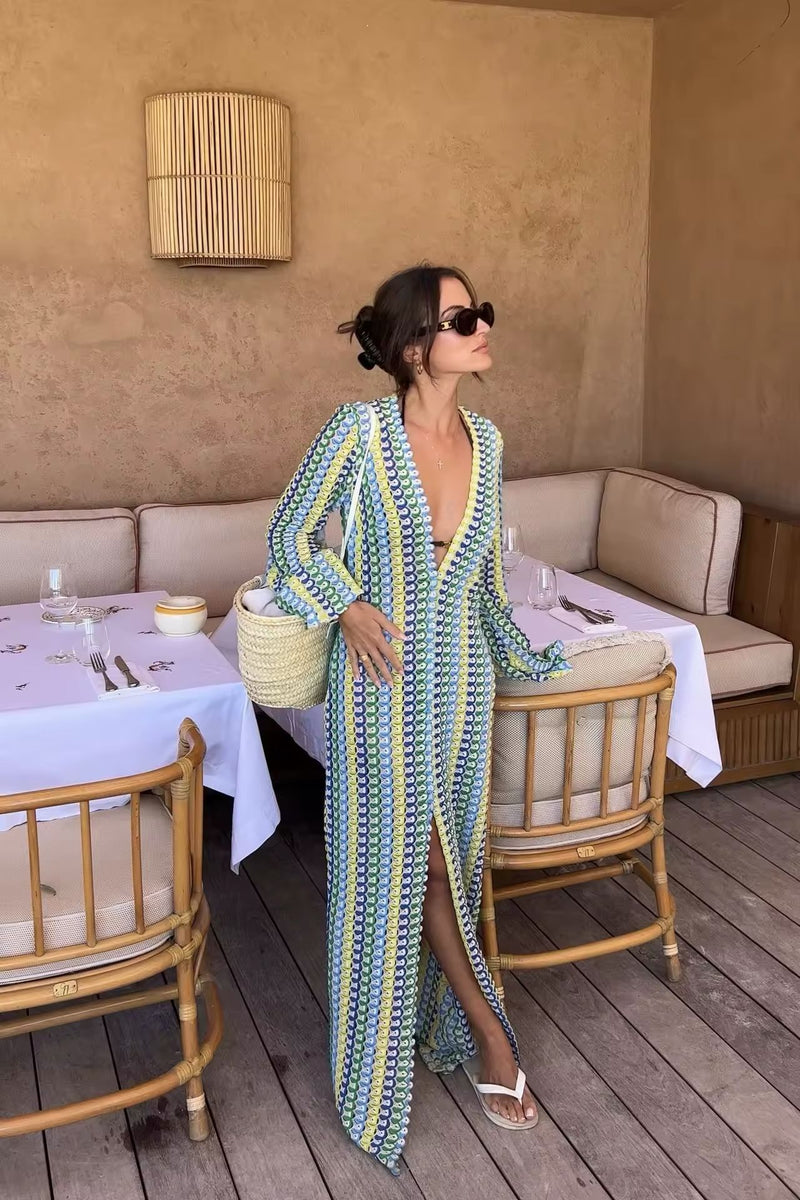 Frau trägt ein buntes Crochet Maxi Dress mit V-Neck, Flare Sleeves und hohem Schlitz – perfekt für Summer Vibes, Boho Chic Looks & Italian Riviera Feelings. Light knit, feminine silhouette, ideal für Beach Clubs & Sunset Moments.
