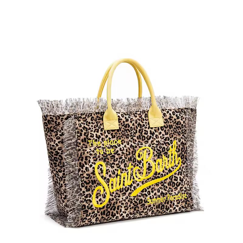 Close-up of thick canvas beach bag with The place to be – Saint Barth” print and raw fringe edges in bohemian summer style.