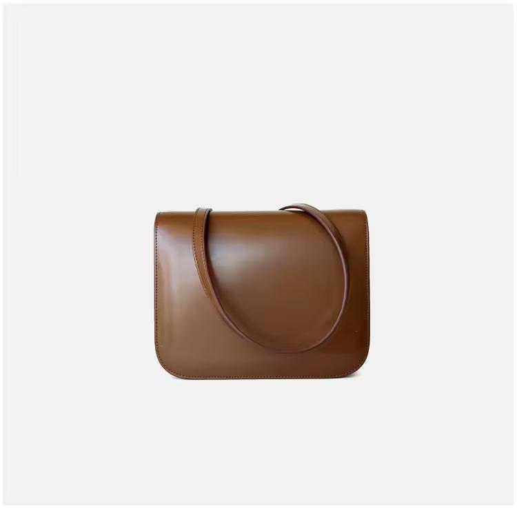 Classic cognac brown leather shoulder bag with gold clasp and soft texture — warm-toned minimalist leather accessory for fall and winter.