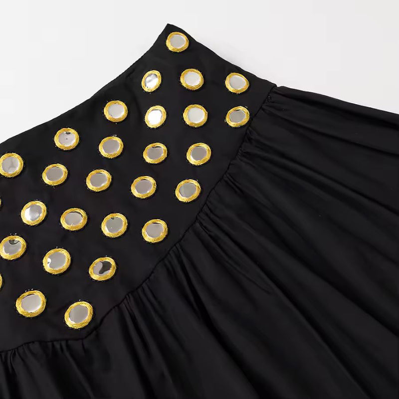 Detail shot of black mini skirt with metallic ring embellishments and soft fabric