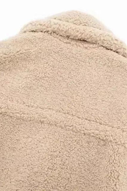 Close-up of beige teddy coat fabric – soft, fluffy lamb fleece texture showing high-quality faux shearling material.
