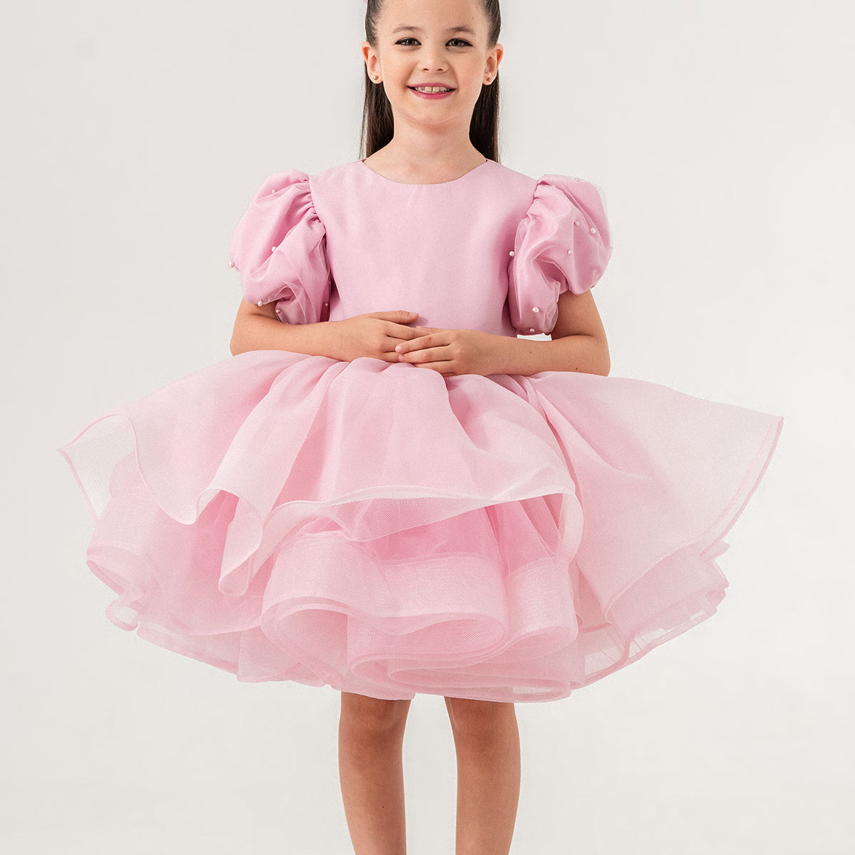 Luxury blush pink princess dress for toddler girls featuring elegant hand-sewn pearl embellishments on puff sleeves, a voluminous layered tulle skirt, and a dramatic oversized bow at the back. Perfect for birthdays, weddings, flower girl moments, and formal occasions. Soft 100% cotton lining for sensitive skin. Couture-inspired, handmade design for unforgettable childhood memories. Ideal for premium kids fashion, special occasion outfits, and baby girl party dresses. Elegant toddler outfit with invisible zi