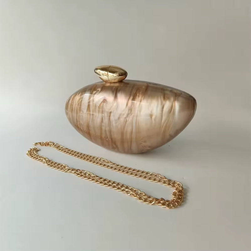Bridal evening clutch in shell-inspired design with smooth acrylic surface and luxurious gold accents.