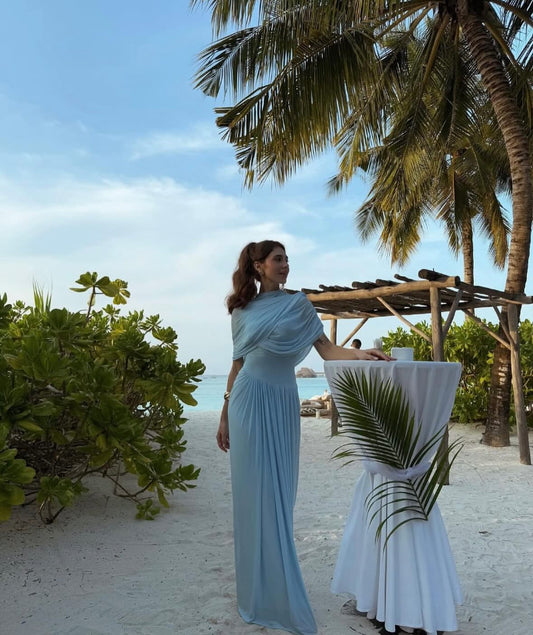 Sky blue draped chiffon evening gown named Chantelle, featuring elegant soft pleats, shoulder wrap detail, and floor-length silhouette – perfect for weddings, galas, and formal events.