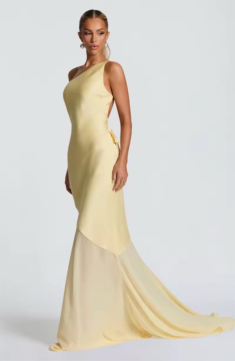Model wearing champagne yellow formal dress with open back and high slit illusion – resort party outfit
