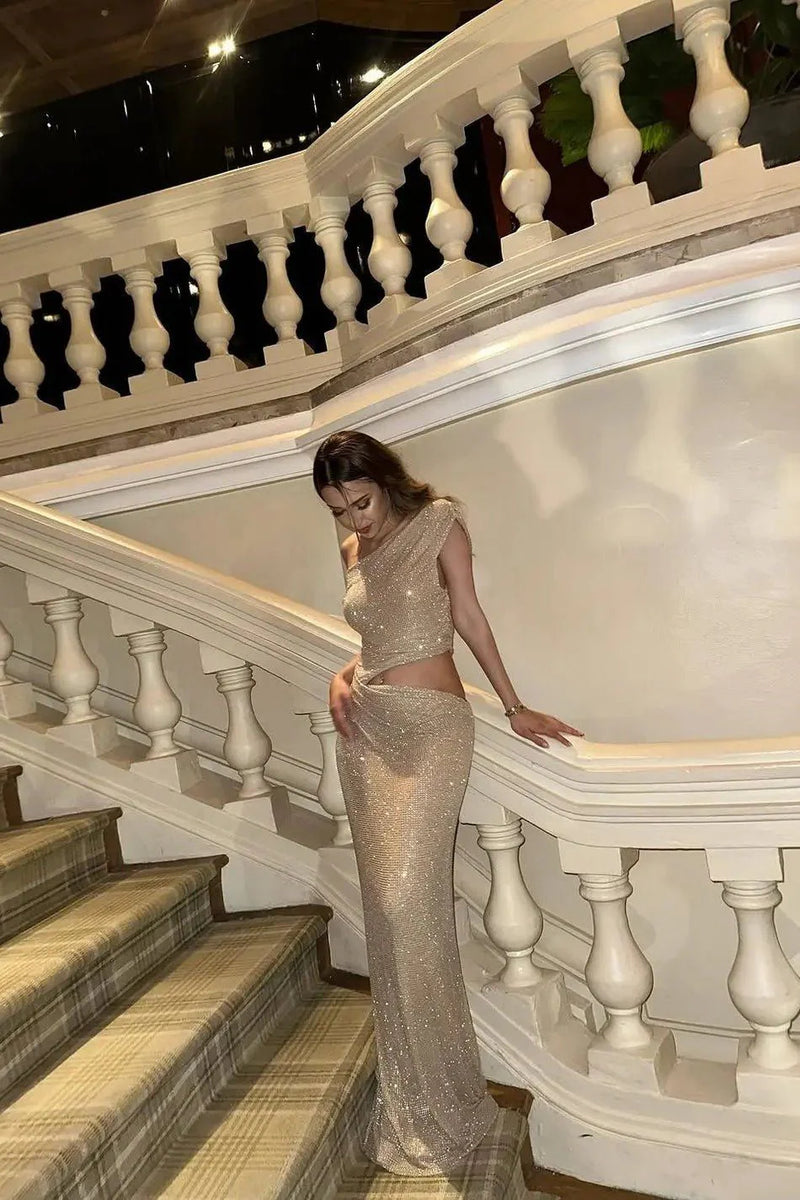 Full-body view of model in the Elena Dress – golden lighting accentuates the sleek cutout waist and elegant drape.