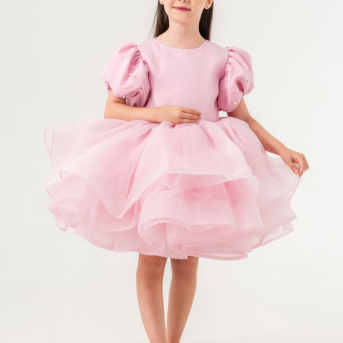 Luxury blush pink princess dress for toddler girls featuring elegant hand-sewn pearl embellishments on puff sleeves, a voluminous layered tulle skirt, and a dramatic oversized bow at the back. Perfect for birthdays, weddings, flower girl moments, and formal occasions. Soft 100% cotton lining for sensitive skin. Couture-inspired, handmade design for unforgettable childhood memories. Ideal for premium kids fashion, special occasion outfits, and baby girl party dresses. Elegant toddler outfit with invisible zi