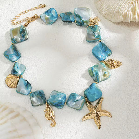 Detailed view of Mira del Mar boho necklace – gold starfish, turtle, shell and turquoise sea charms
