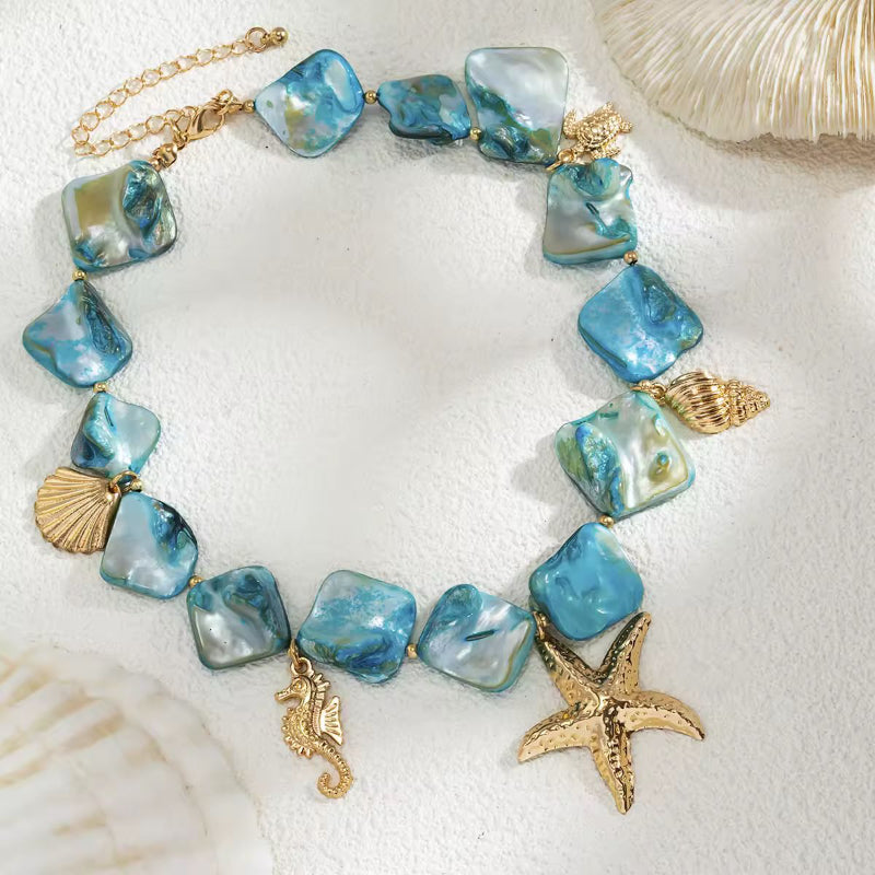 Detailed view of Mira del Mar boho necklace – gold starfish, turtle, shell and turquoise sea charms
