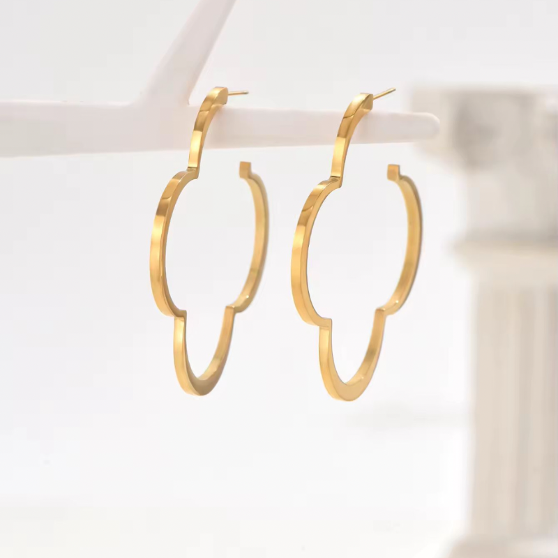 Trendy gold floral statement hoop earrings worn on ear – large clover-shaped copper earrings for women, fashion jewelry 2025
