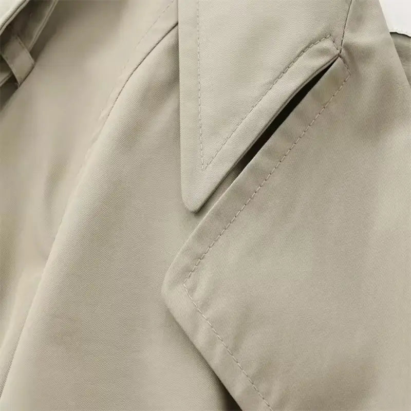 Beige double-breasted coat with black buttons, adjustable belt, and shoulder epaulets, designed for stylish and comfortable wear. Perfect for every occasion, made from high-quality polyester and crafted in Italy.