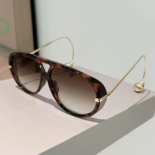 Fashion sunglasses with tortoise frame and gold temples, frontal view.
