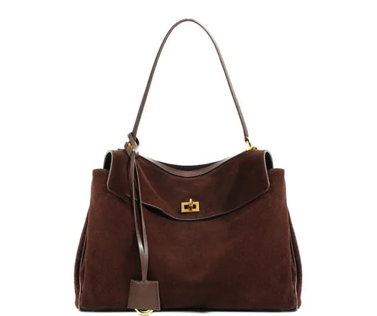 The Elegance Suede Handbag is a true masterpiece crafted from high-quality suede, blending luxury and functionality perfectly. Available in two elegant colors – Light Brown and Dark Brown – this exquisite bag features a sophisticated gold buckle, enhancing its design and adding a modern yet timeless look. With generous dimensions of 23 cm x 11 cm x 35 cm, it offers ample space for all your essentials, from smartphones to cosmetics and more, making it the ideal companion for any occasion.

