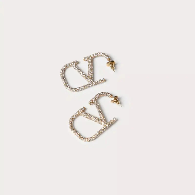 Elegant V-shaped earrings made of 18 karat gold-plated material with sparkling Zirkonia stones, offering a luxurious, diamond-like shine. These medium-sized earrings with a modern V design add a sophisticated touch to any outfit, perfect for both everyday wear and special occasions.