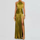 Model wearing a shimmering gold-olive pleated halter neck maxi dress with high slit and ruched waistband, styled with gold jewelry and platform heels – front view.