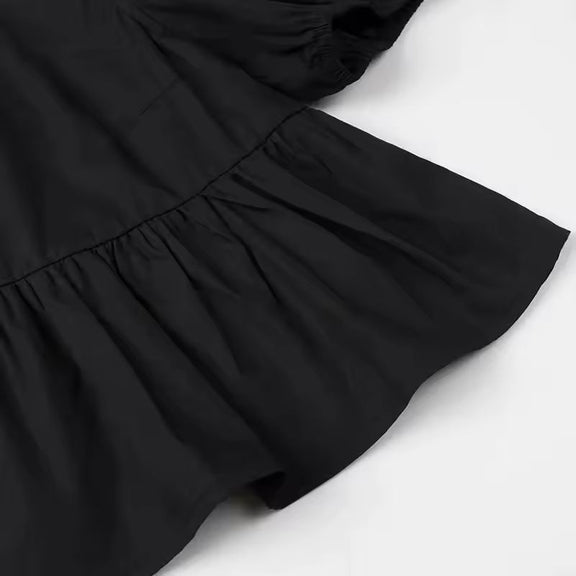 Black tie-front summer blouse with puff sleeves and soft flared hem, trendy and bold casual wear for women.