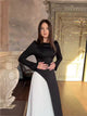 Back view of Warda Dress – black long sleeve maxi dress with lace-up waist and white pleated panel

