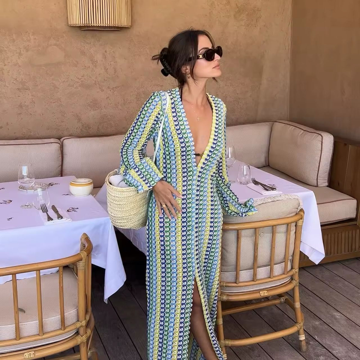 Frau trägt ein buntes Crochet Maxi Dress mit V-Neck, Flare Sleeves und hohem Schlitz – perfekt für Summer Vibes, Boho Chic Looks & Italian Riviera Feelings. Light knit, feminine silhouette, ideal für Beach Clubs & Sunset Moments.