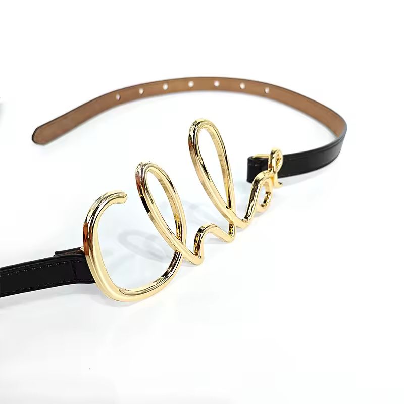 Minimalist black genuine leather belt with gold-tone script buckle, high fashion style
