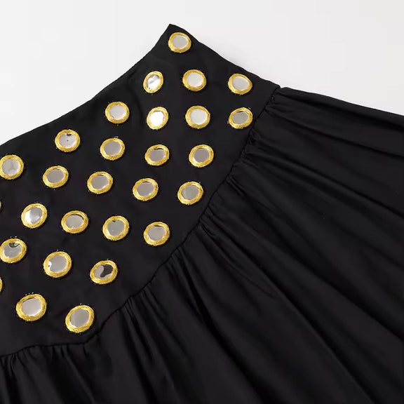 Detail shot of black mini skirt with metallic ring embellishments and soft fabric
