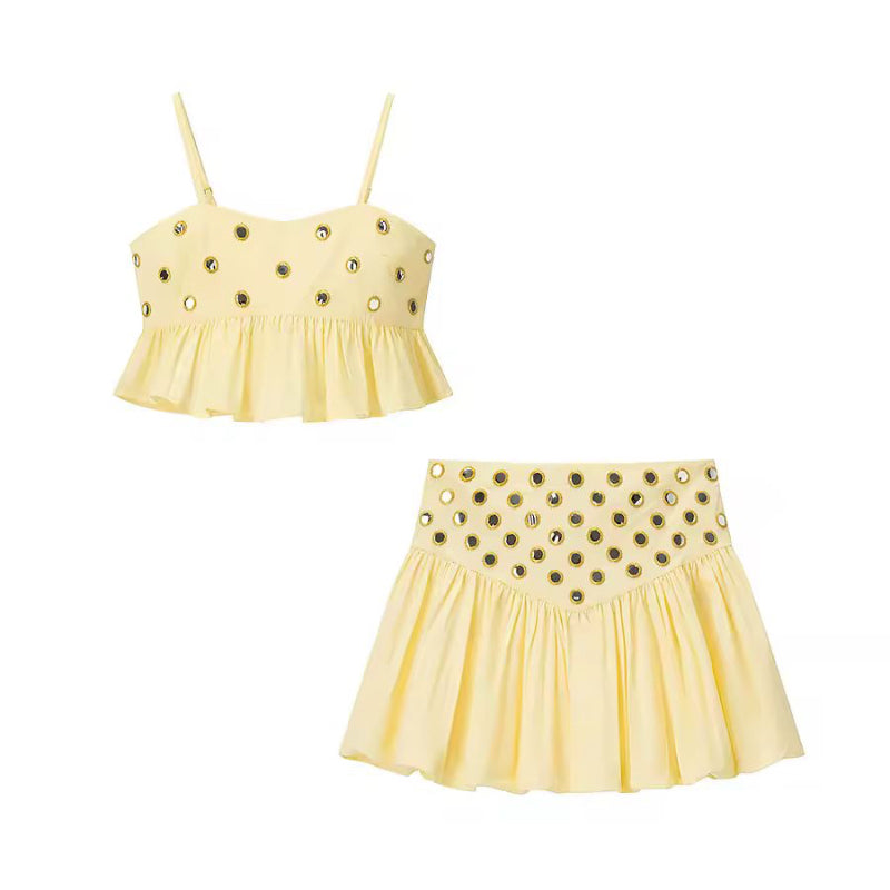 Woman wearing yellow ZAYA 2-piece skirt set with eyelet crop top and pleated high waist mini skirt by the sea
