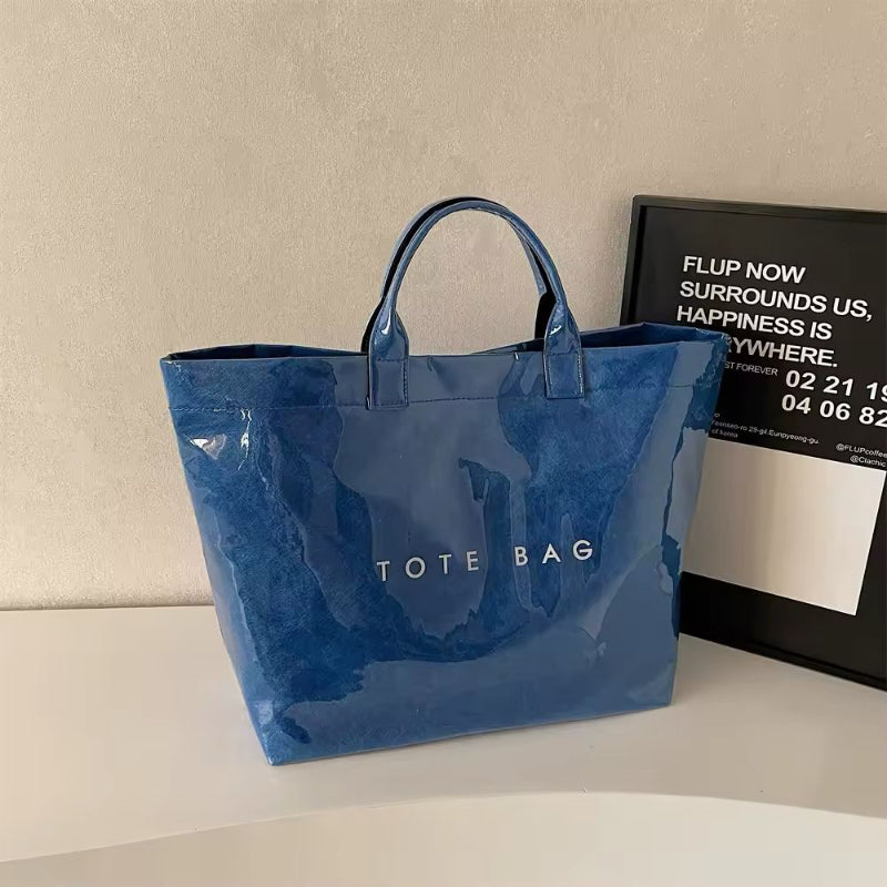 Transparent waterproof jelly tote bag in glossy PVC with bold letter print, shown in modern color variations – ideal for beach, city shopping, moms, and travel. Stylish large capacity handbag with short handles.