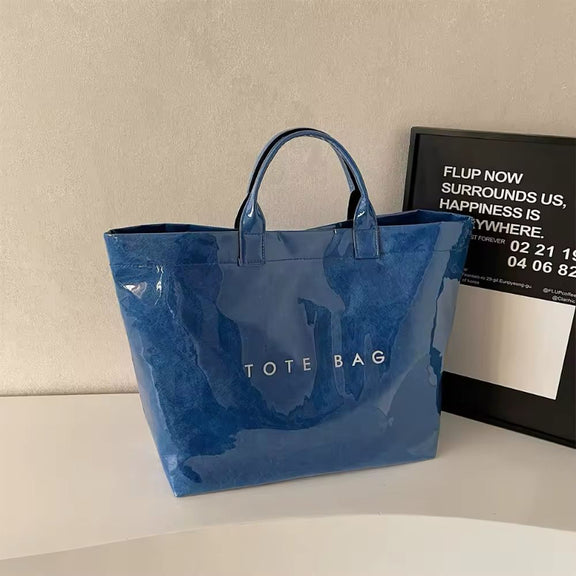 Transparent waterproof jelly tote bag in glossy PVC with bold letter print, shown in modern color variations – ideal for beach, city shopping, moms, and travel. Stylish large capacity handbag with short handles.